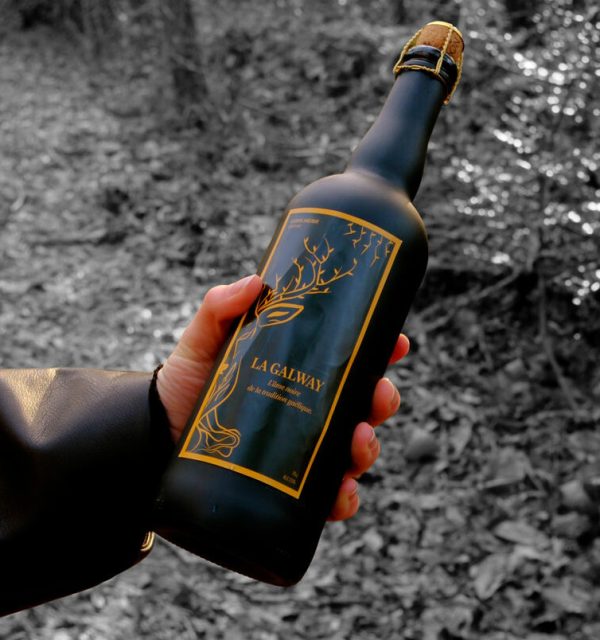 Une main tient la bière noire La Galway, bière de tradition gaélique brassée artisanalement par Le Gouel Gaélique.
